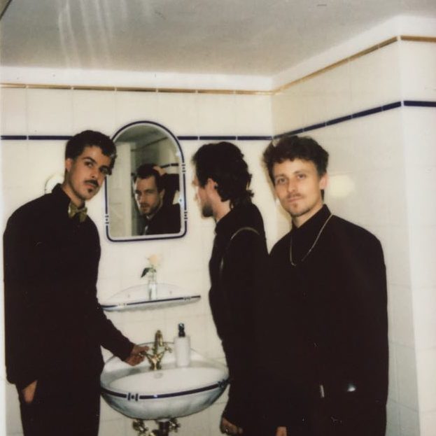 Three musicians dressed in black in a bathroom (Nicolas Greiner, Johannes Bode, Lukas Growe)